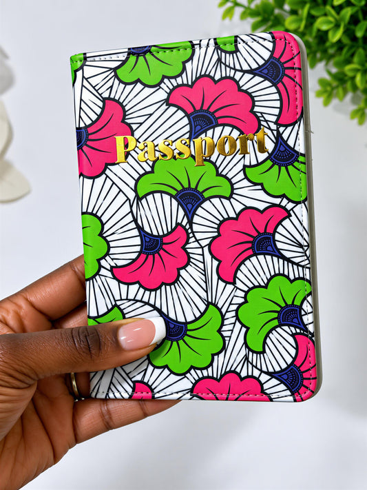 A hand holding a colorful passport wallet with a floral pattern in pink, green, and white.