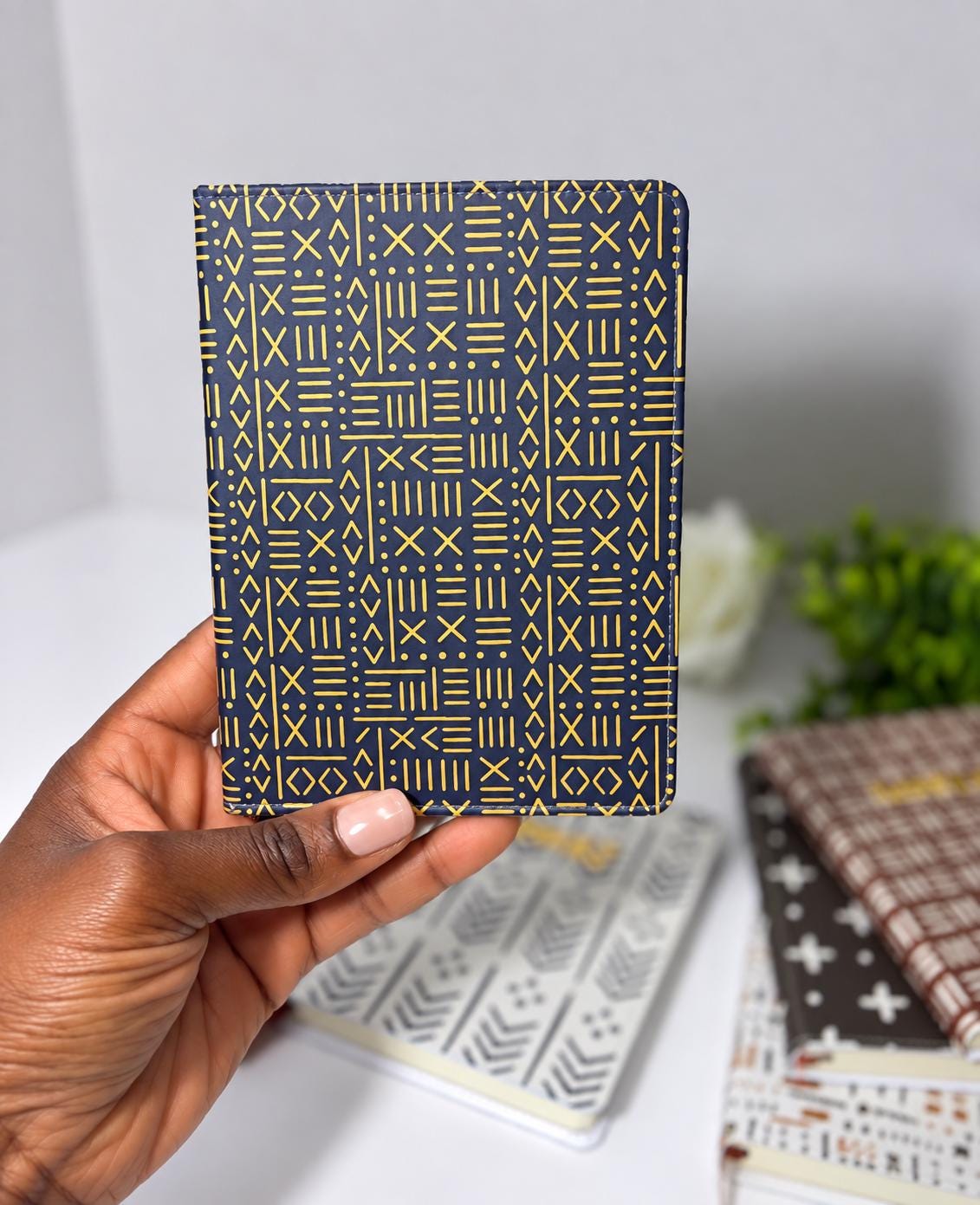 A hand holding a black and gold patterned wallet or card case against a white background.
