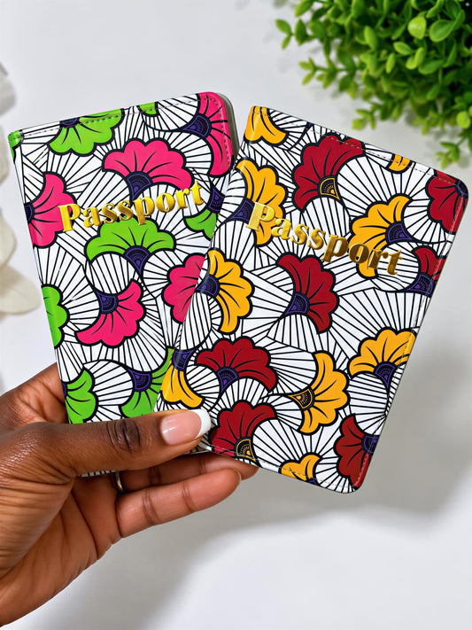 A hand holding a colorful passport-style wallet with a floral pattern.