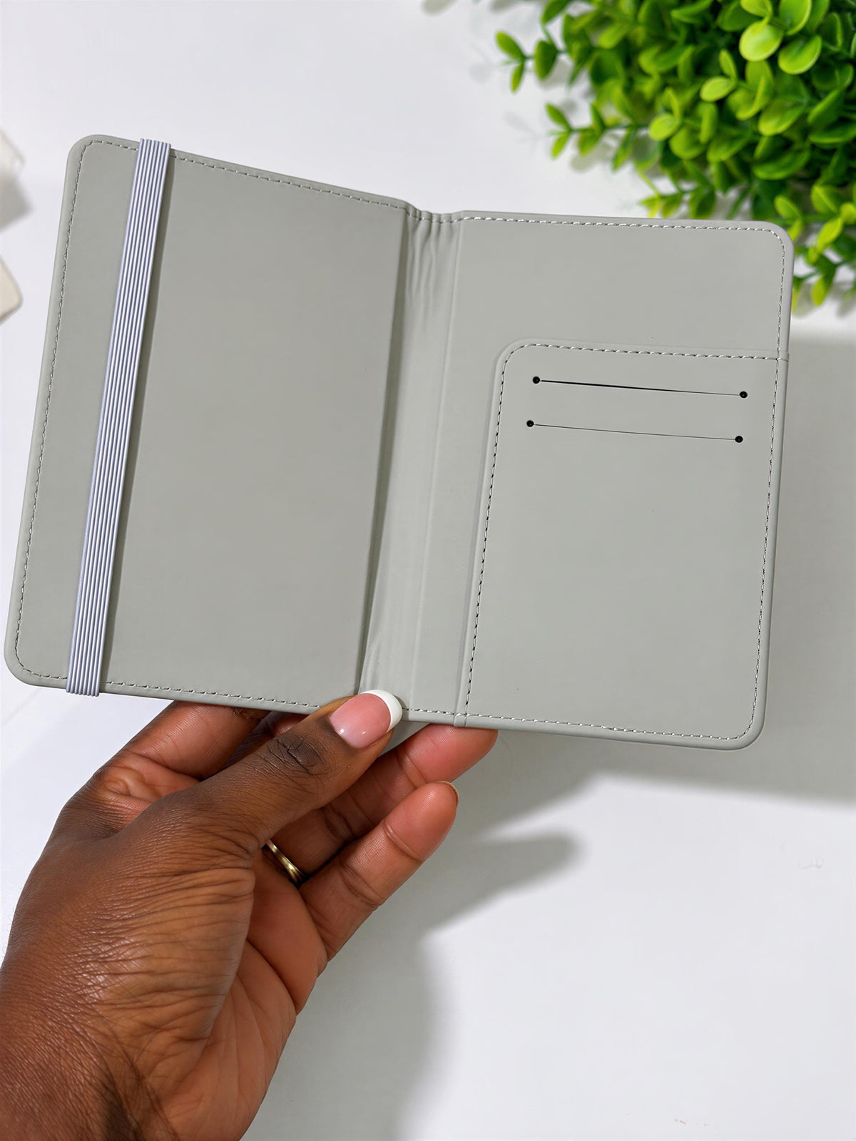 A hand holding a gray wallet or card holder with a white stripe.