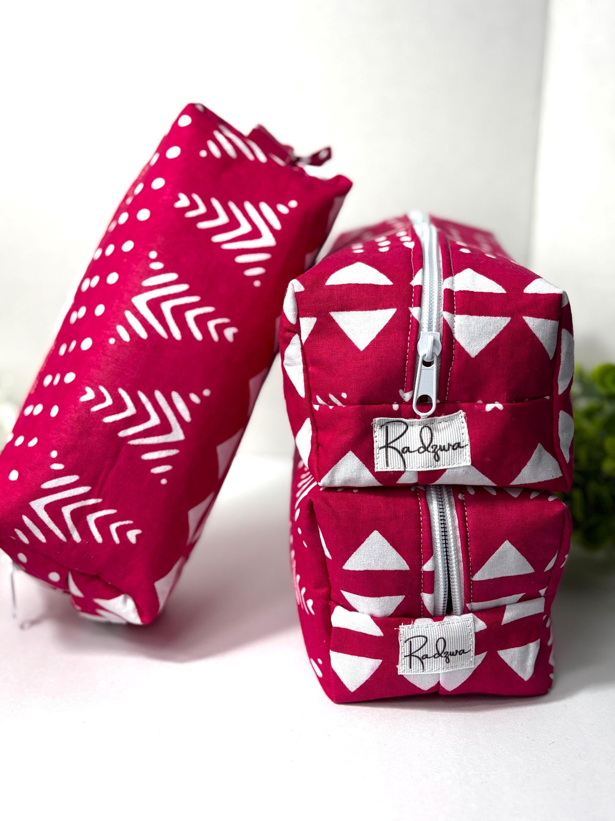 two pink and white patterned bags with zippers, placed on a white surface.