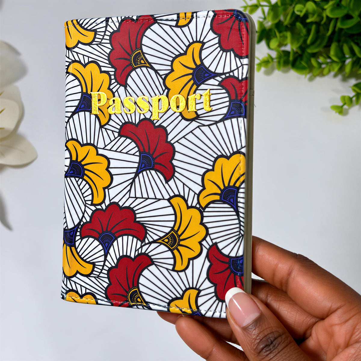 A colorful passport holder with a floral pattern is being held in a hand.