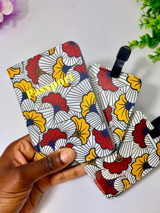 A hand holding a colorful passport holder with a floral pattern, against a white background with some greenery visible in the background.