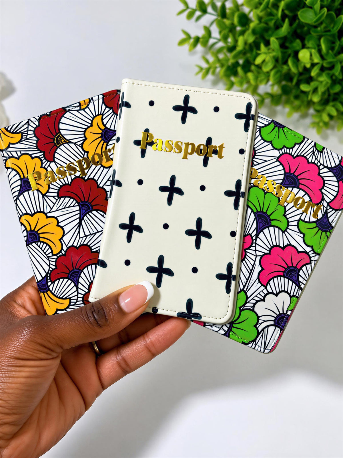 A hand holding two colorful patterned passport holders against a white background.