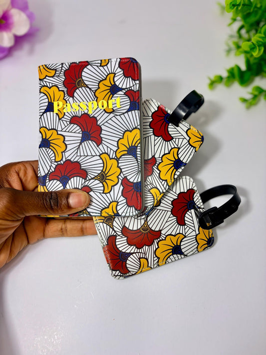A hand is holding a colorful passport holder with a floral pattern, and there are two smaller luggage tags attached to it.
