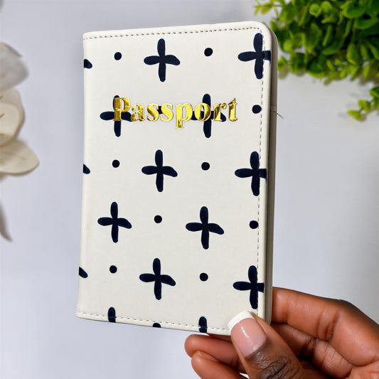 A hand holding a white passport holder with a black cross pattern and the word "Passport" printed on it.